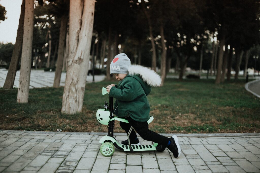 Kid riding scooter in front of trees